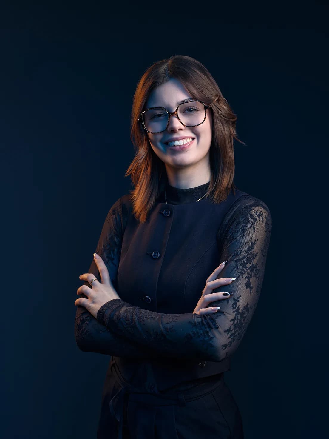 Portrait d’Élise Rouget, bras croisés, sur fond bleu nuit