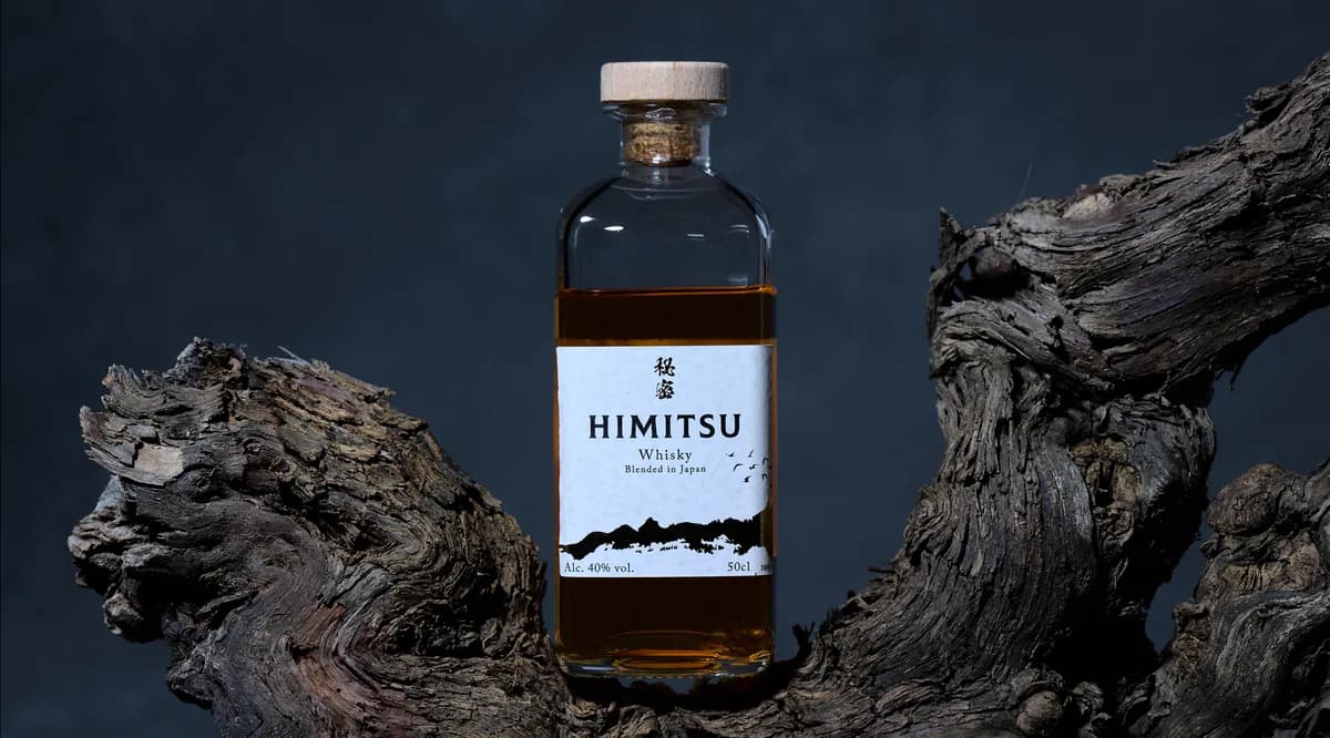 Bouteille de whisky Himitsu posée contre un bois flotté