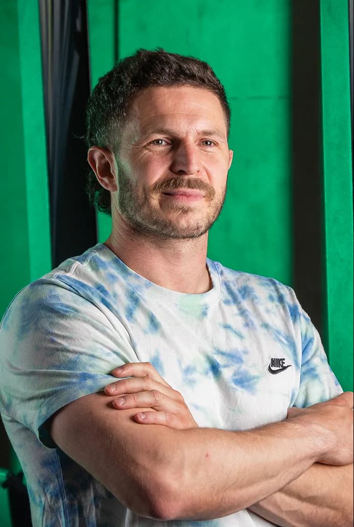Portrait d’un sportif en t-shirt tie-dye, bras croisés, sur fond vert
