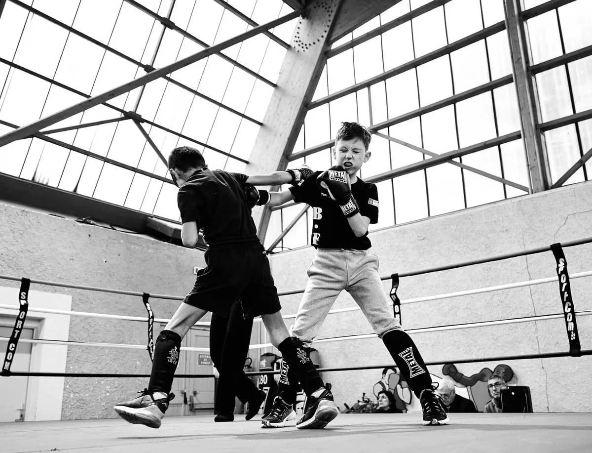 Deux jeunes boxeurs en plein combat sous une verrière, en noir et blanc