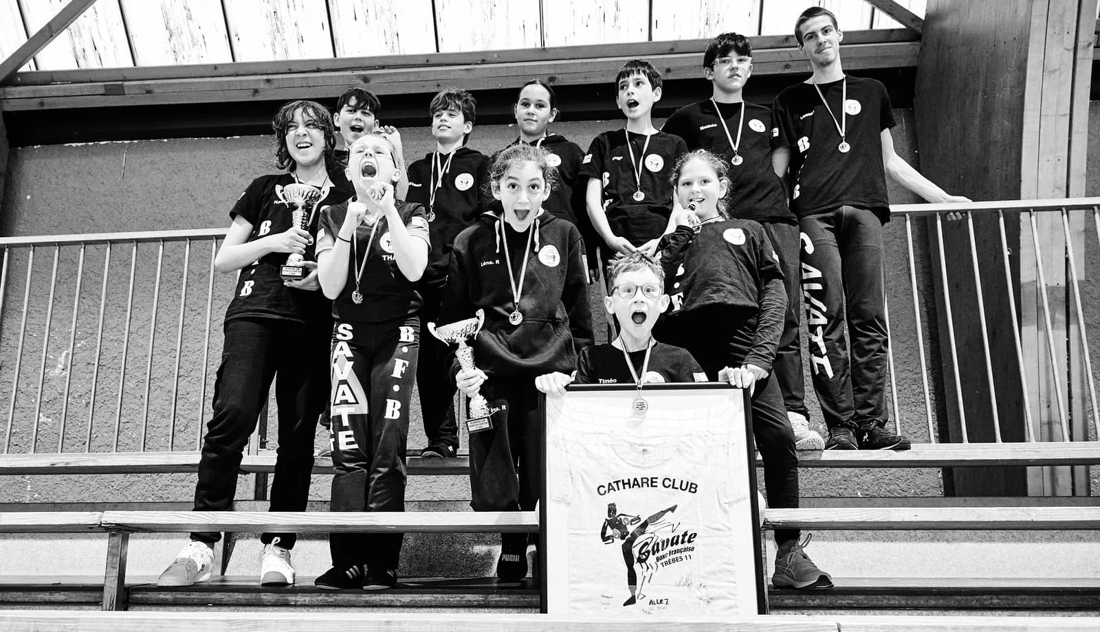 Jeunes boxeurs du club de savate médaillés, criant de joie dans les gradins avec leurs coupes