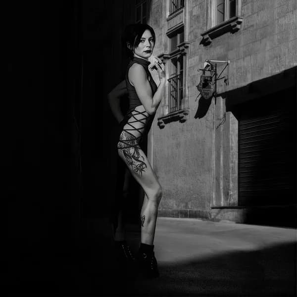 Femme adossée au mur d’une rue la nuit, en noir et blanc