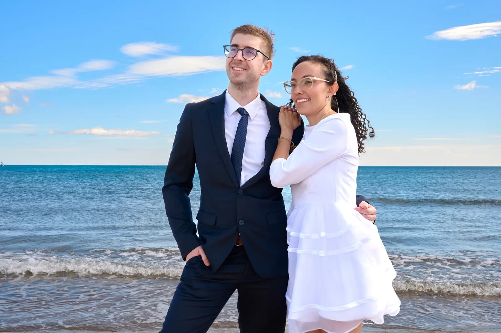 Les mariés debout sur la plage, la mer derrière eux