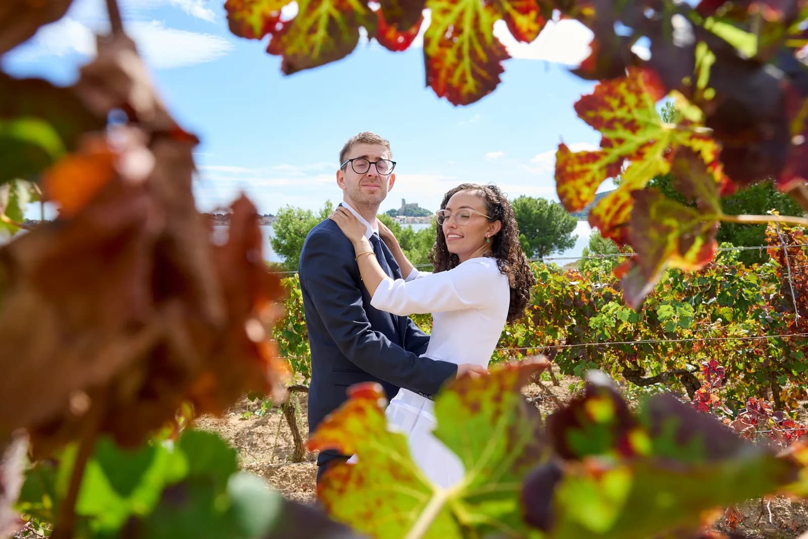 Les mariés enlacés dans une vigne aux feuilles rouges, la mer en arrière-plan